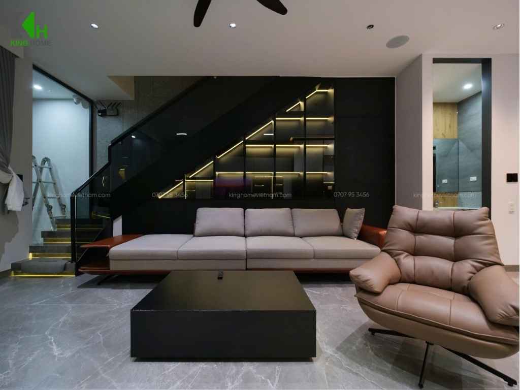 Bộ sofa lớn được đặt dọc theo một bên tường, kết hợp cùng ghế thư giãn và bàn trà trung tâm, tạo thành một khu vực tiếp khách thoải mái cho gia đình