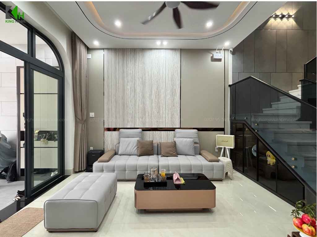 Phòng khách gây ấn tượng với bộ sofa màu trắng kem kết hợp bàn trà mặt kính, tạo cảm giác hiện đại nhưng vẫn ấm áp.